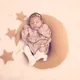 תינוקת ניובורן ישנה בשלווה על כרית ירח עם כוכבים מסביב.